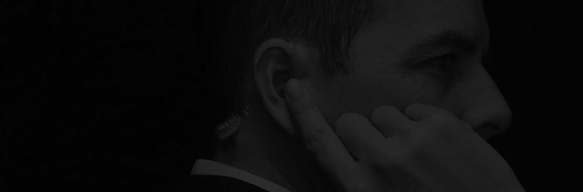 Security officer using an earpiece for communication, representing professional surveillance and protection services.